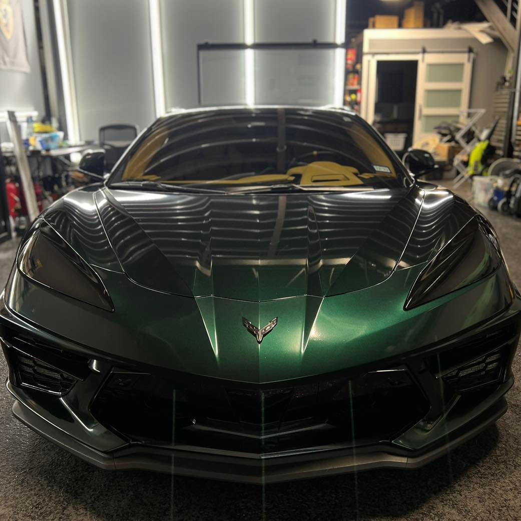 A green sports car is parked in a garage