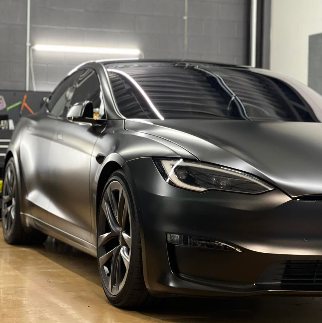 A black tesla model s is parked in a garage