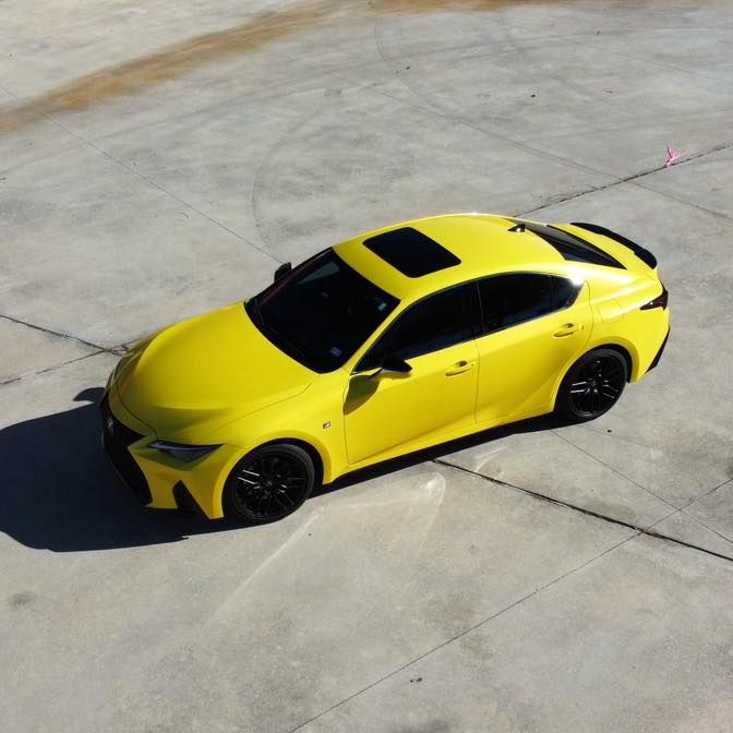 A yellow car is parked on a concrete surface