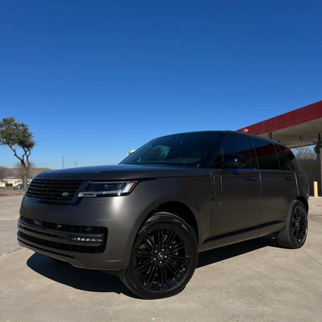 A black range rover is parked in front of a gas station