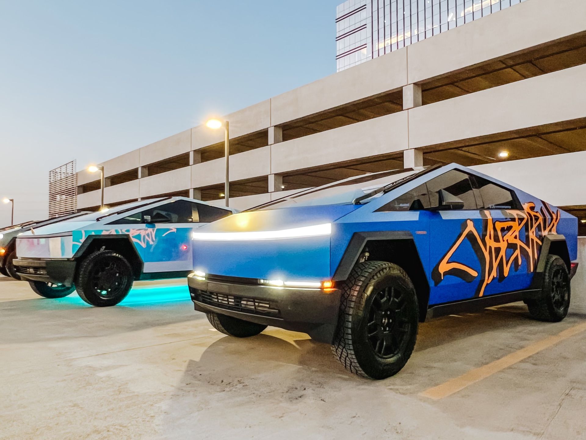 Two blue cars are parked next to each other in a parking lot.