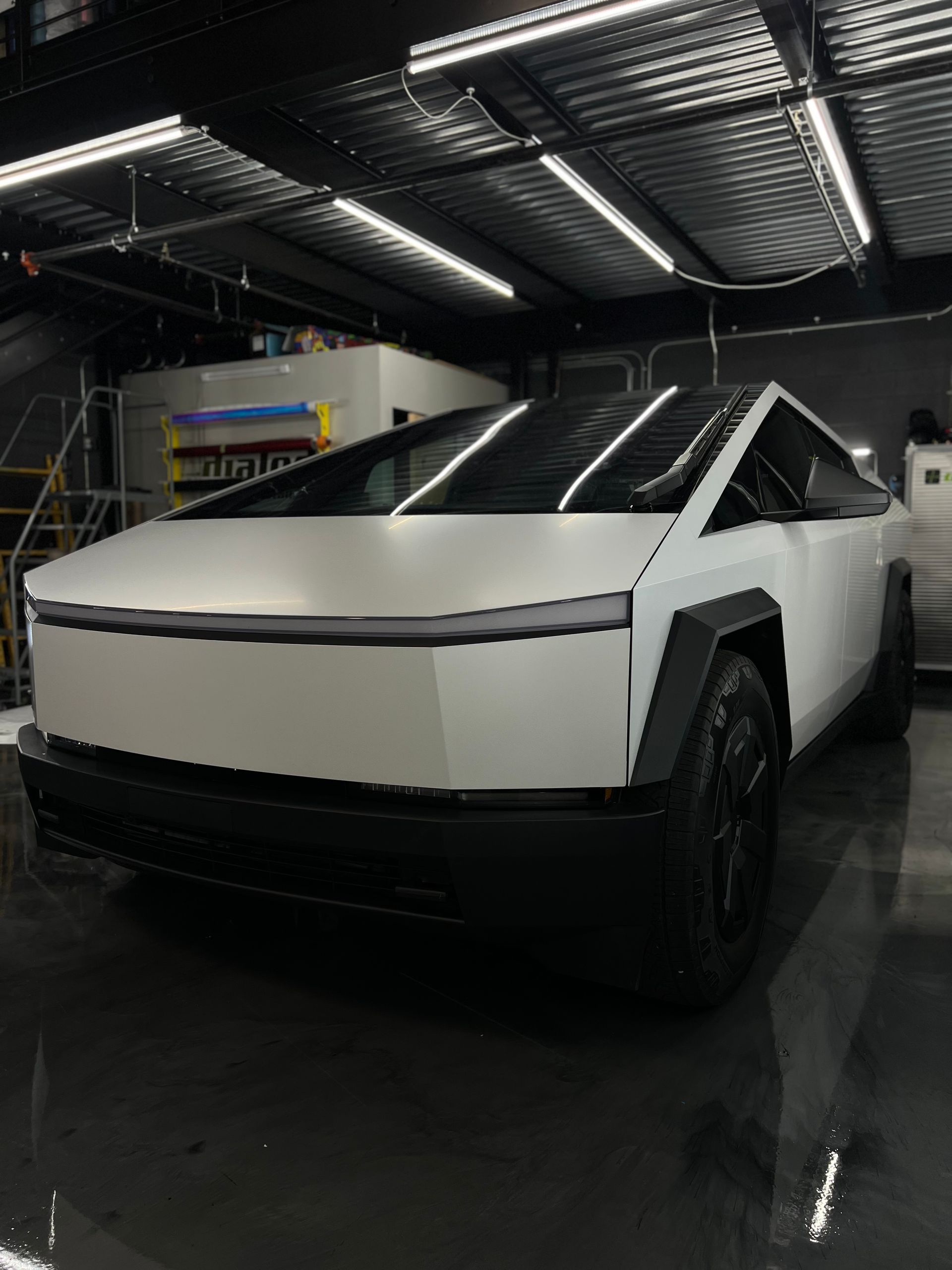 A white tesla cybertruck is parked in a garage.