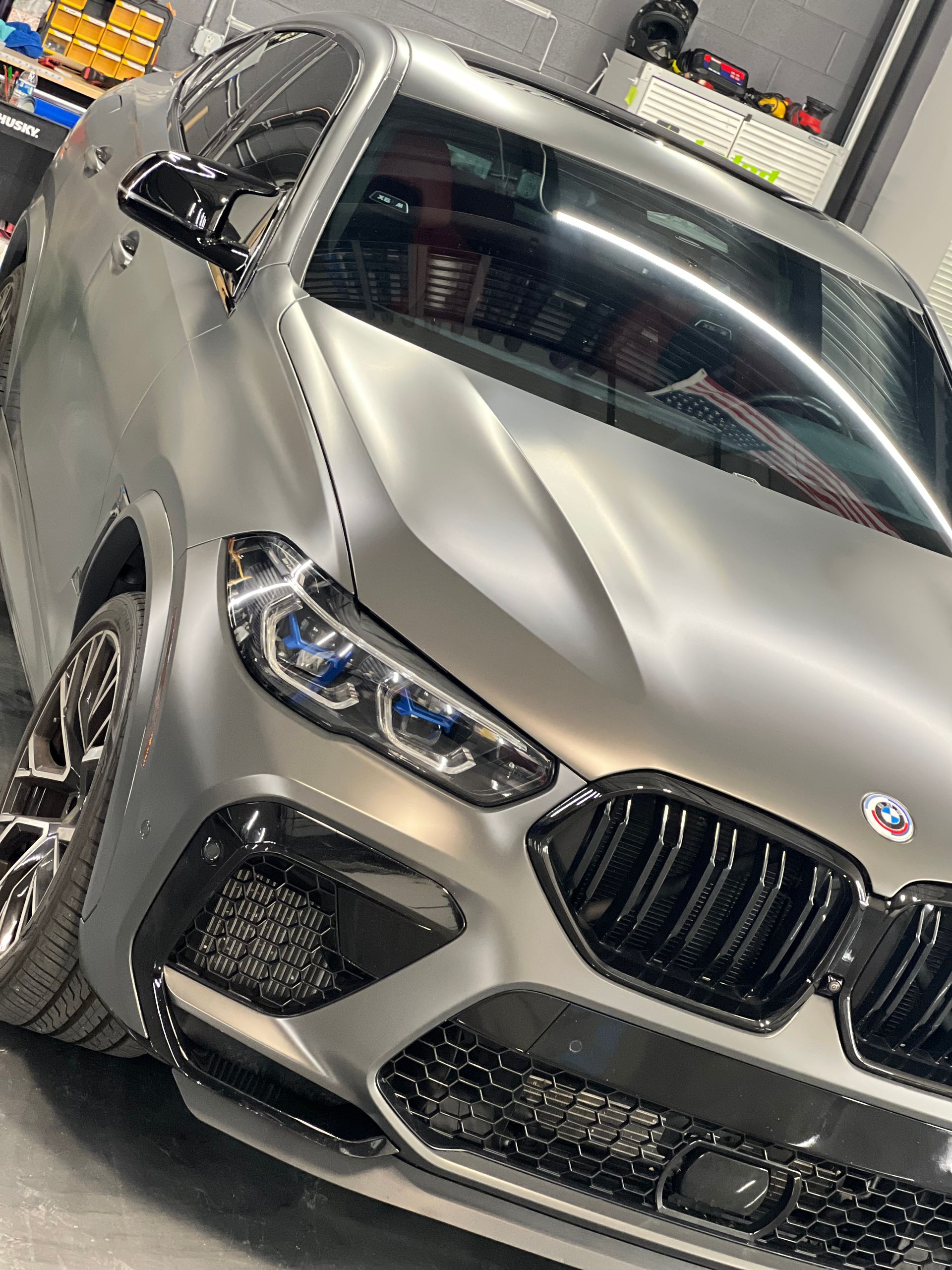 A silver bmw x6 m is parked in a garage.