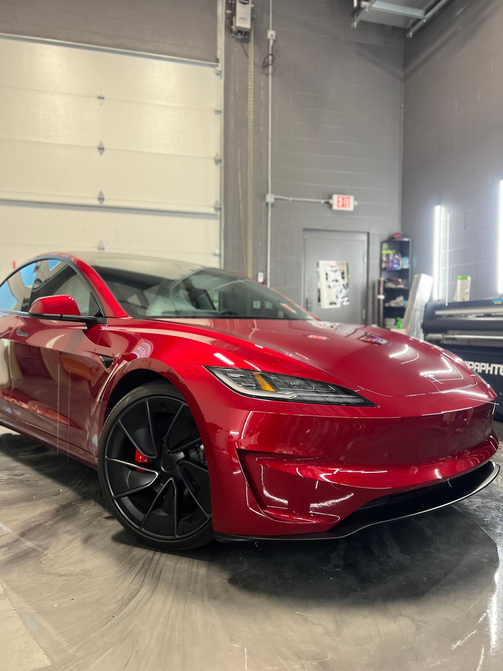 A red tesla model s is parked in a garage.