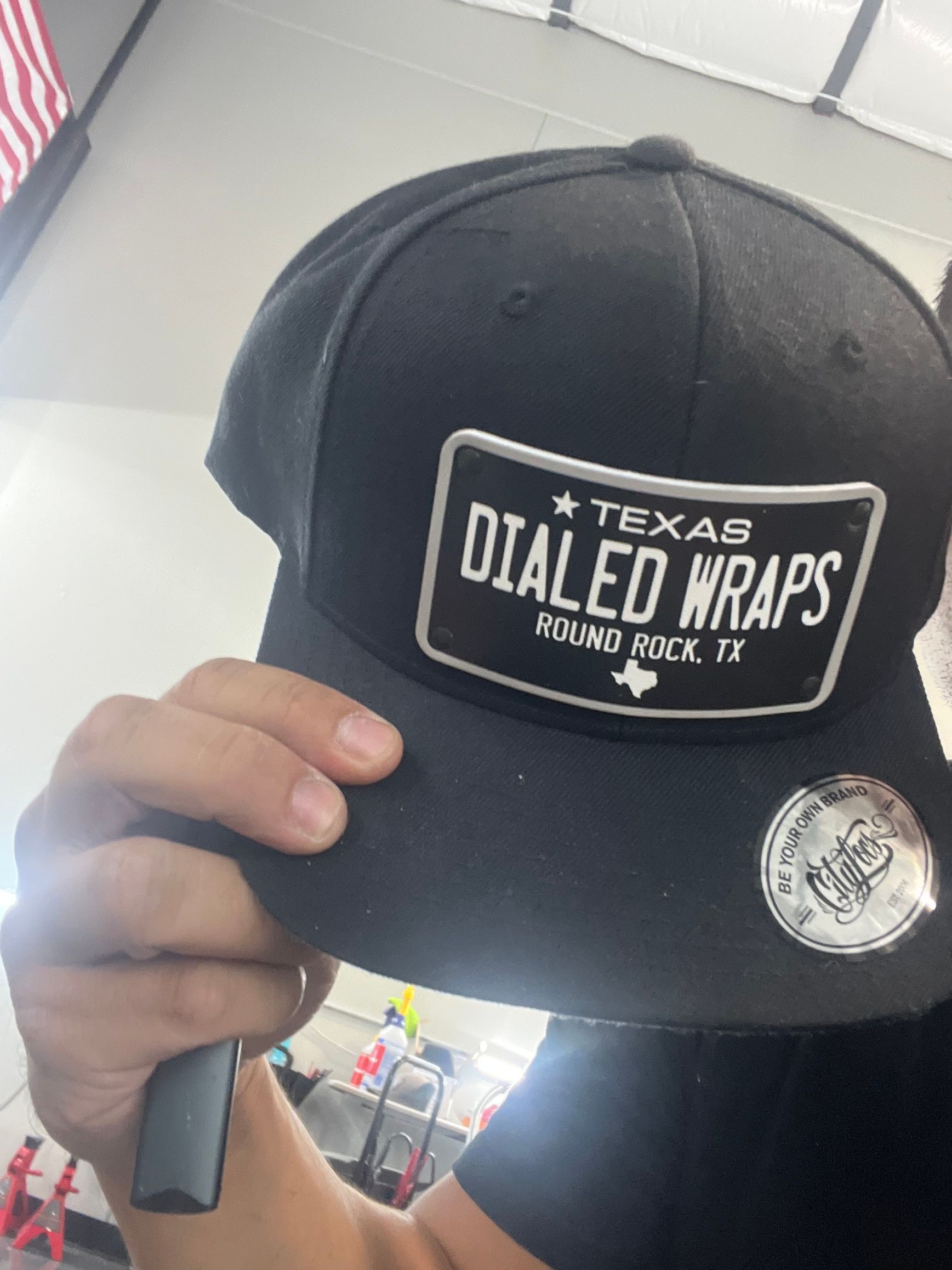 A person is holding a black hat that says texas dialed wraps