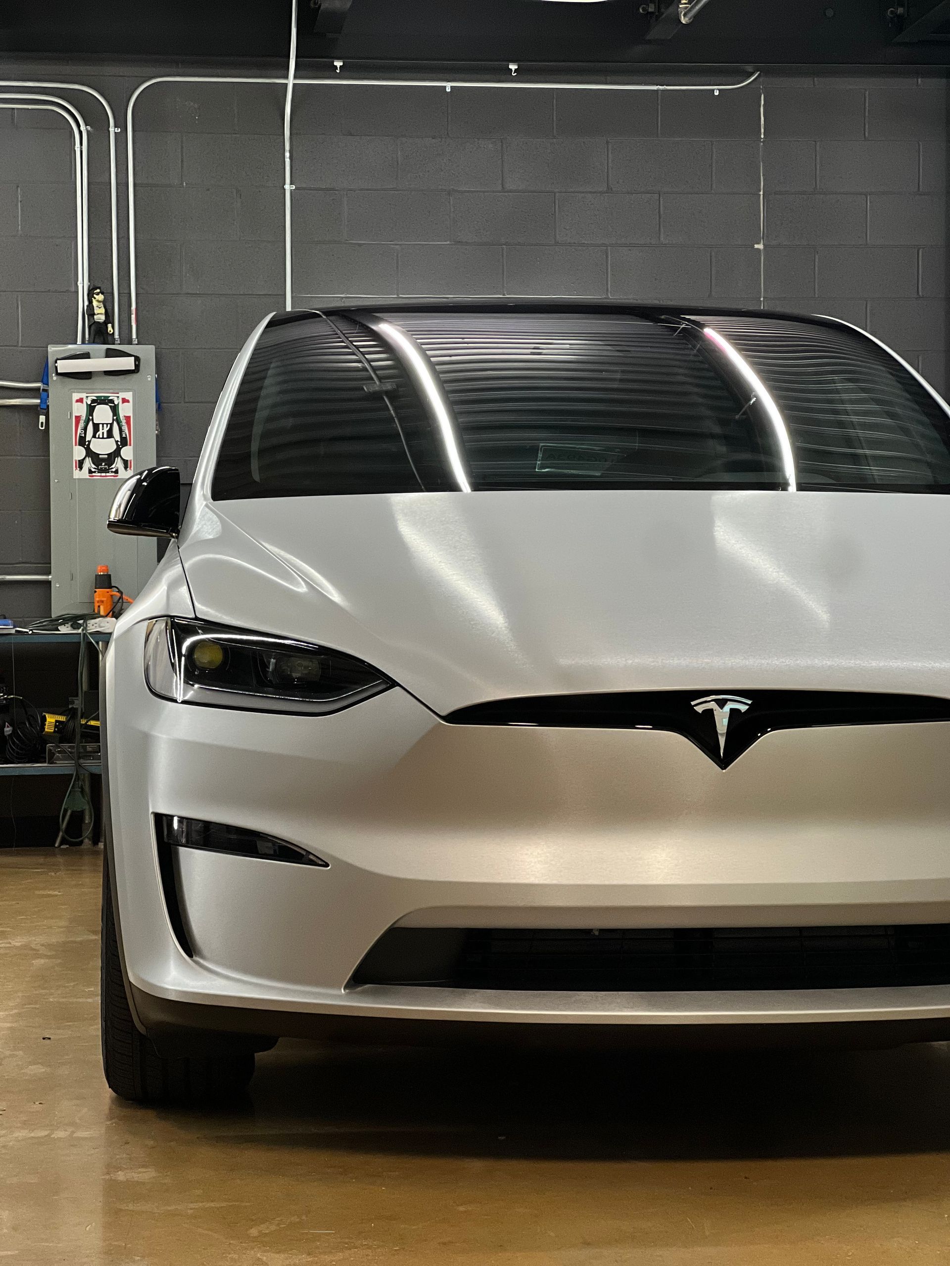 A white tesla model s is parked in a garage.
