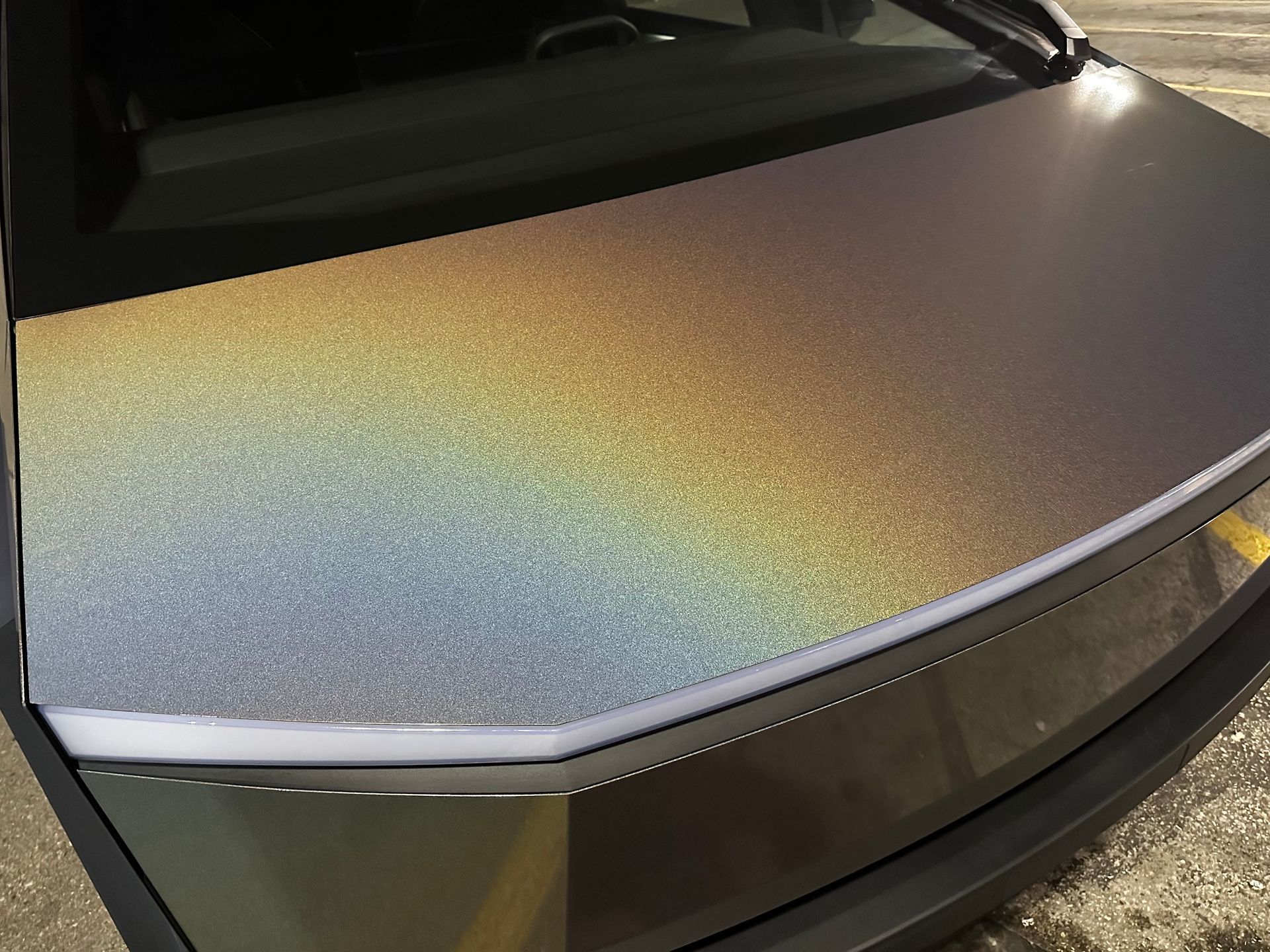 A close up of the hood of a car with a rainbow paint job