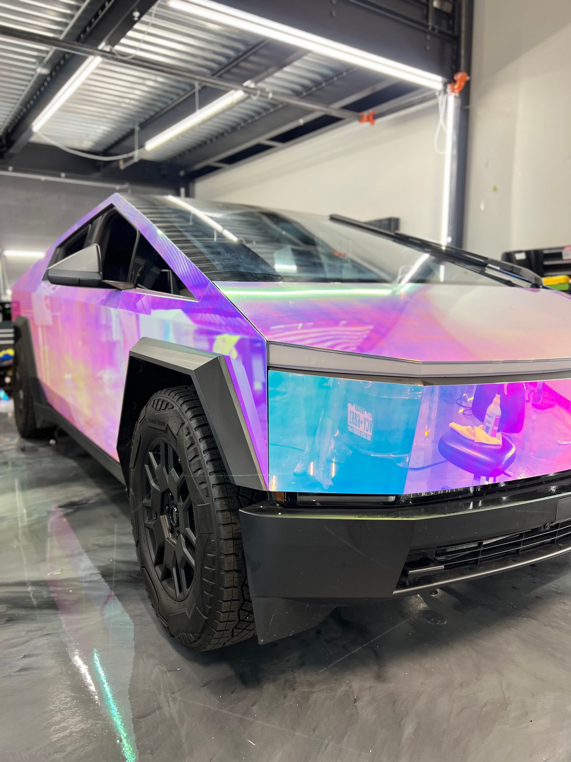 A purple tesla cybertruck is parked in a garage.