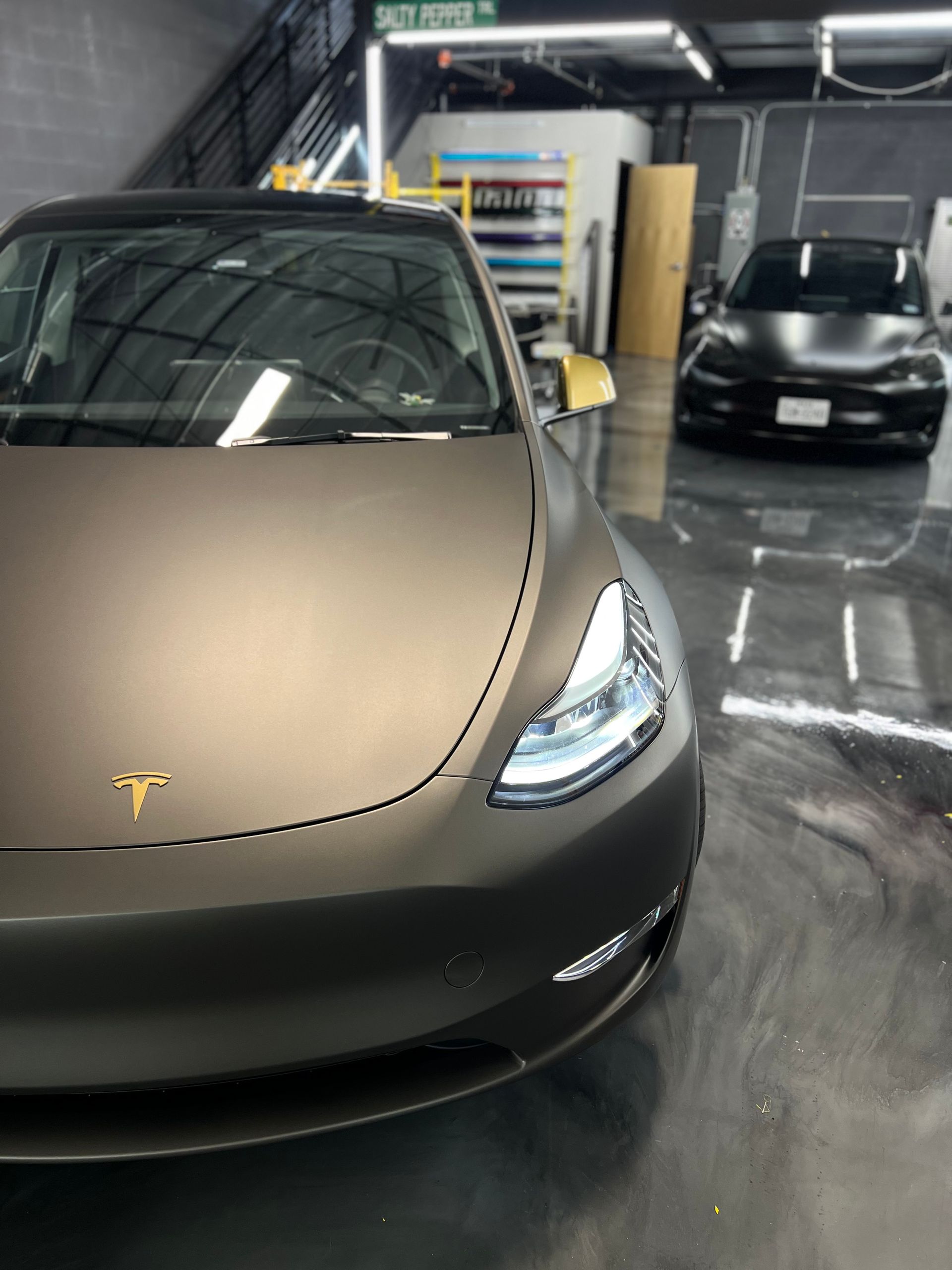 A black tesla model 3 is parked in a garage