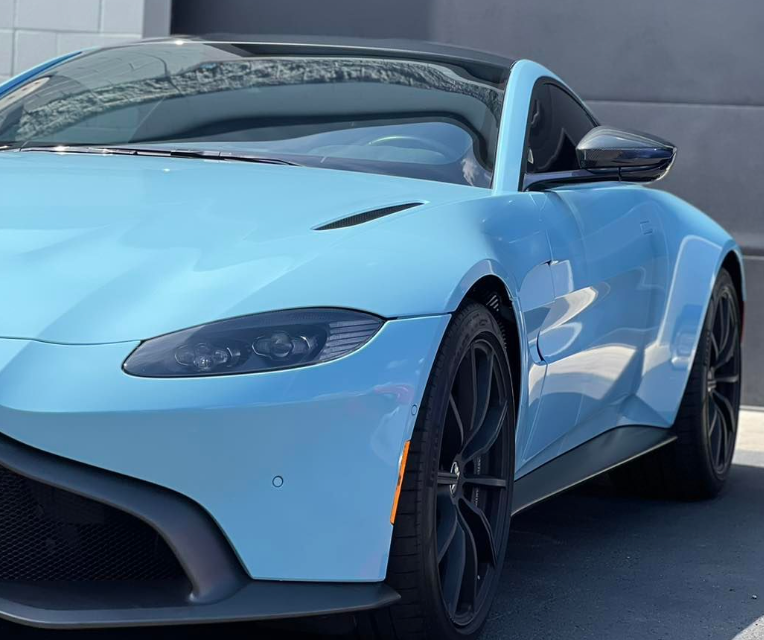 A blue sports car is parked in front of a building