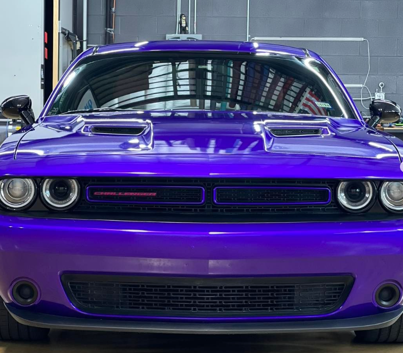 A purple dodge challenger is parked in a garage.