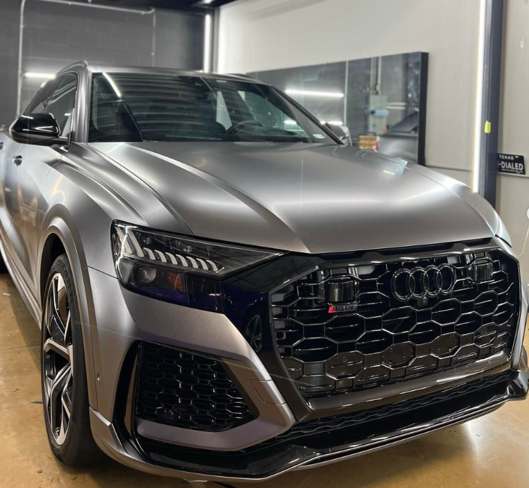 A silver audi q8 is parked in a garage.
