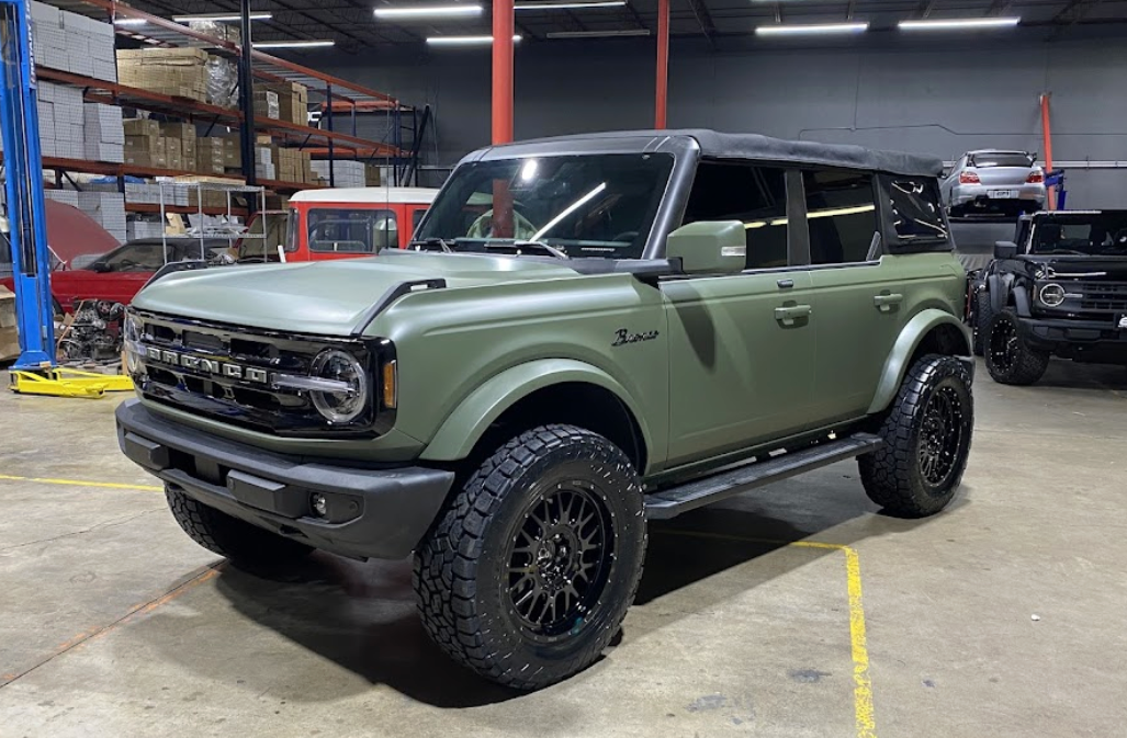 A green ford bronco is parked in a garage.