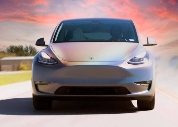A tesla model y is driving down a road