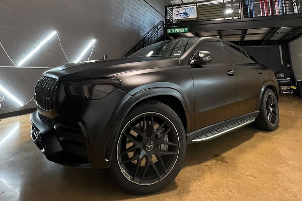 A black mercedes benz gls 63 amg is parked in a garage.