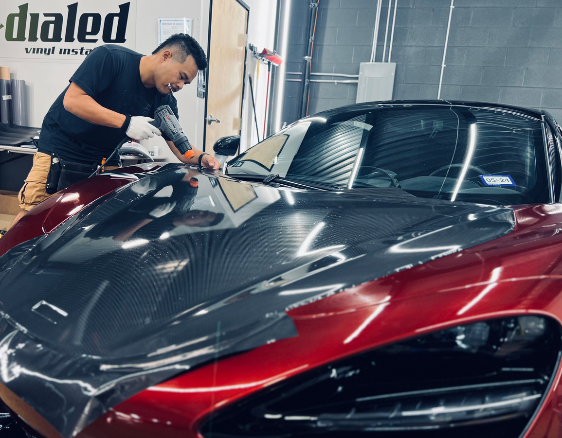 A man is polishing the hood of a red sports car