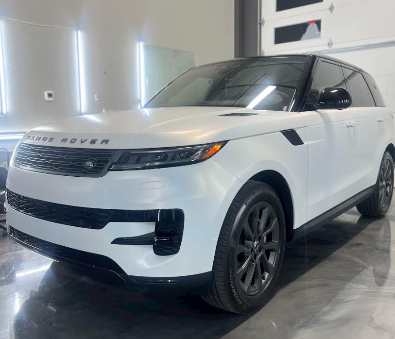 A white range rover is parked in a garage.
