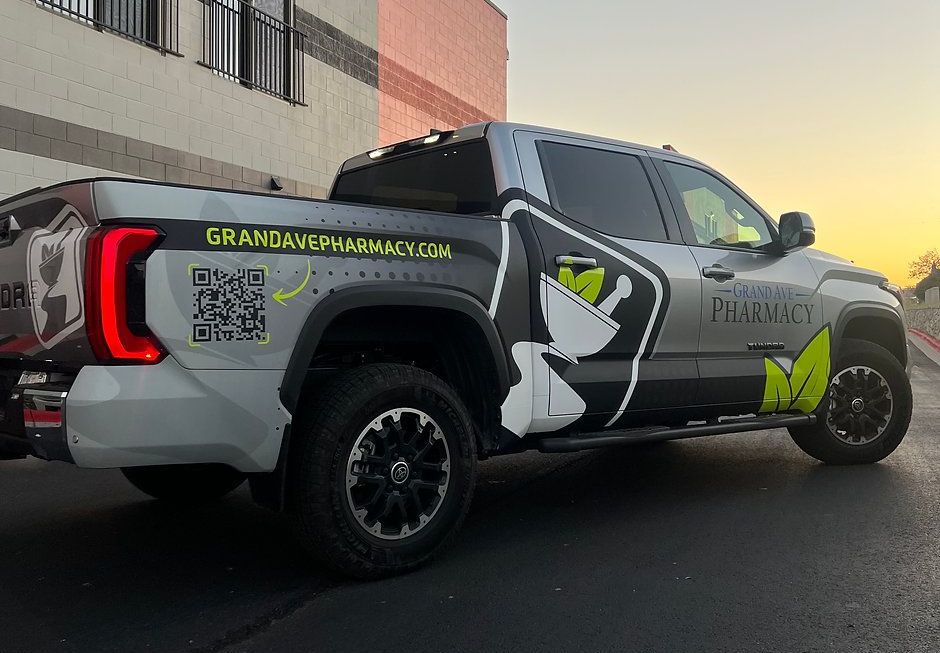 A truck with a wrap on it is parked in front of a building.