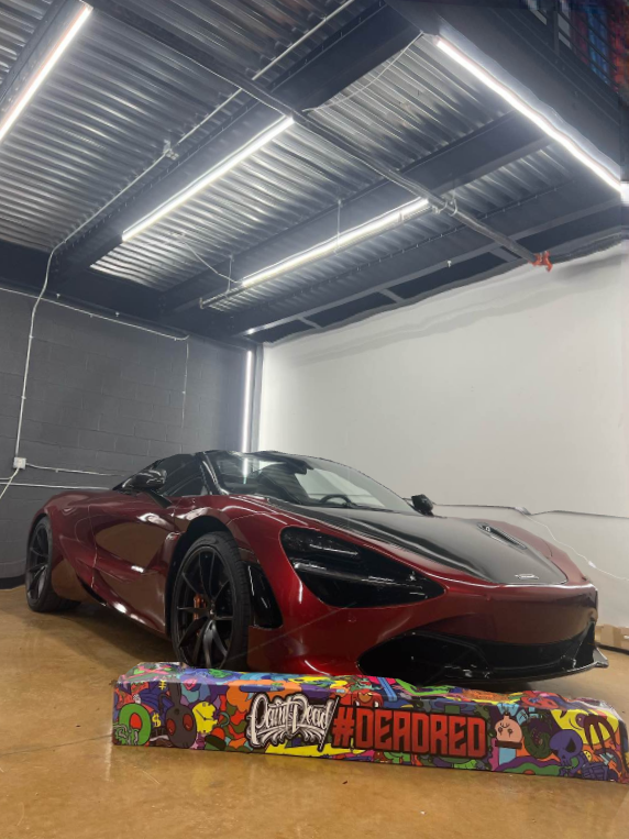 A red sports car is parked in a garage next to a sign.