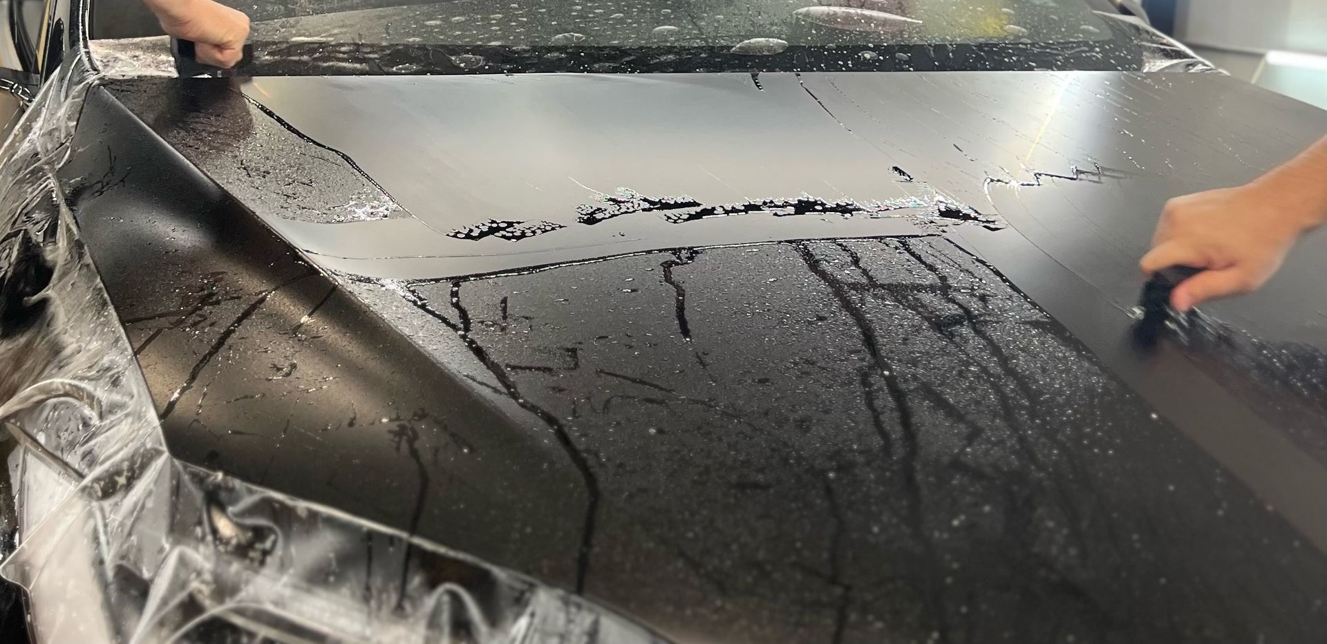 A person is cleaning a black surface with a brush.