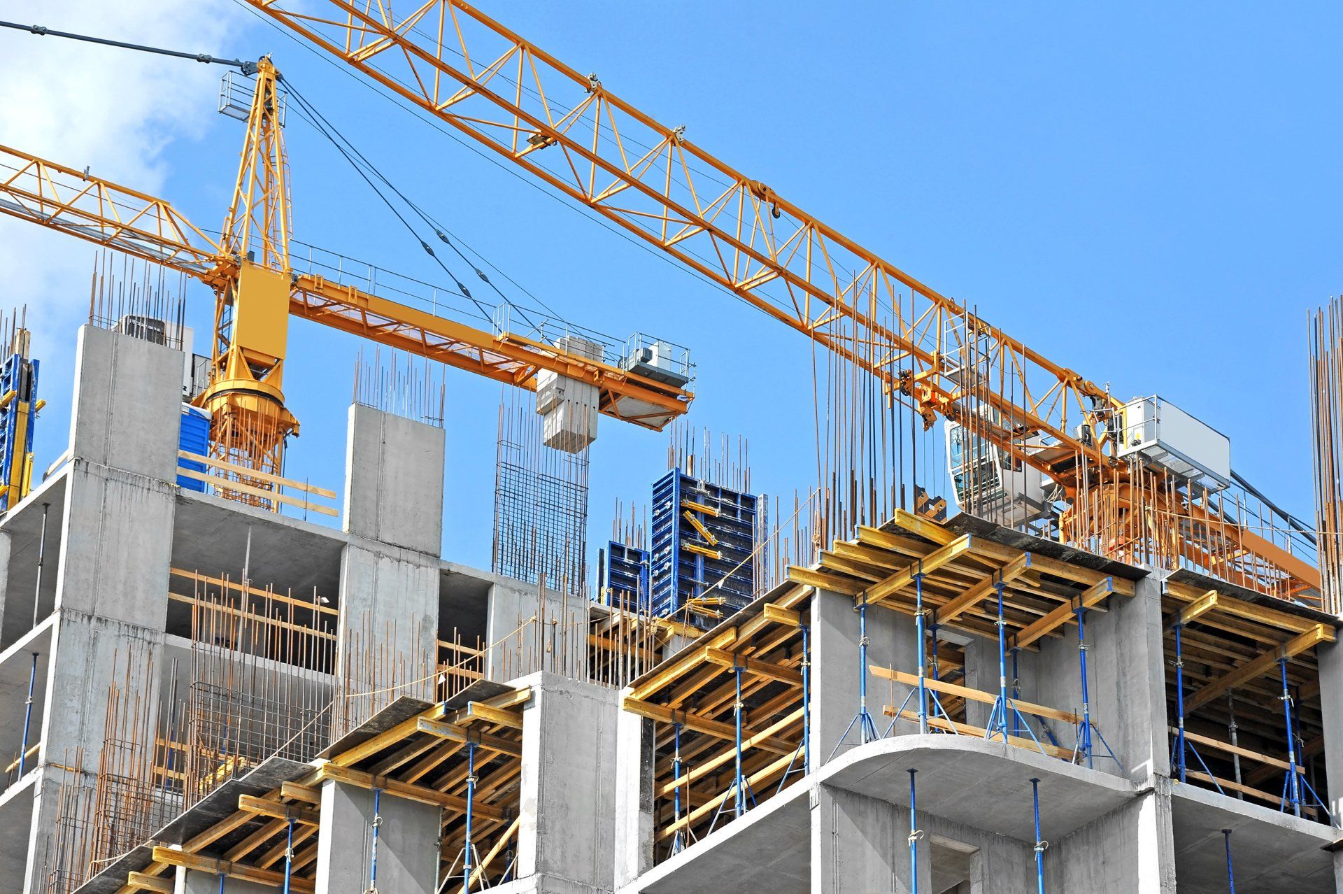 Construction site with yellow crane, concrete structure, and clear blue sky.