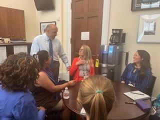 Group of people in a room having a meeting with a man standing.