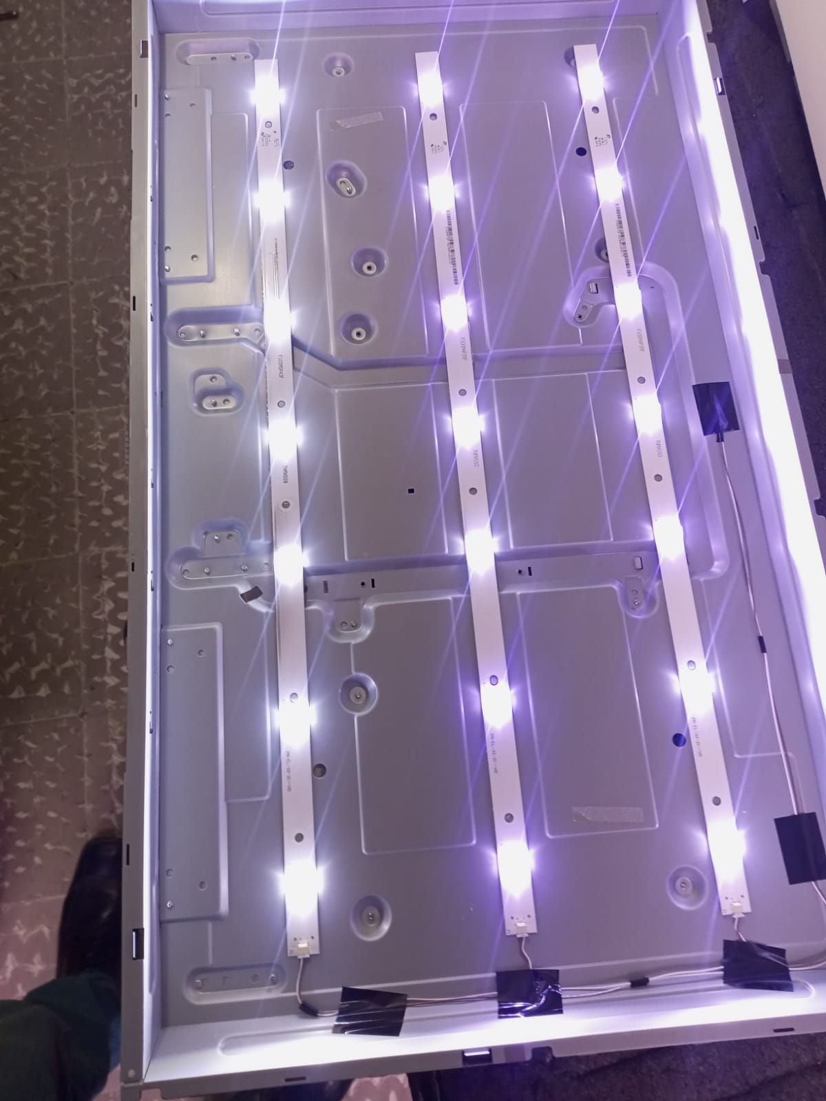 Dispositivo electrónico abierto con tiras de LED encendidas dentro de un chasis plateado, visto desde arriba.