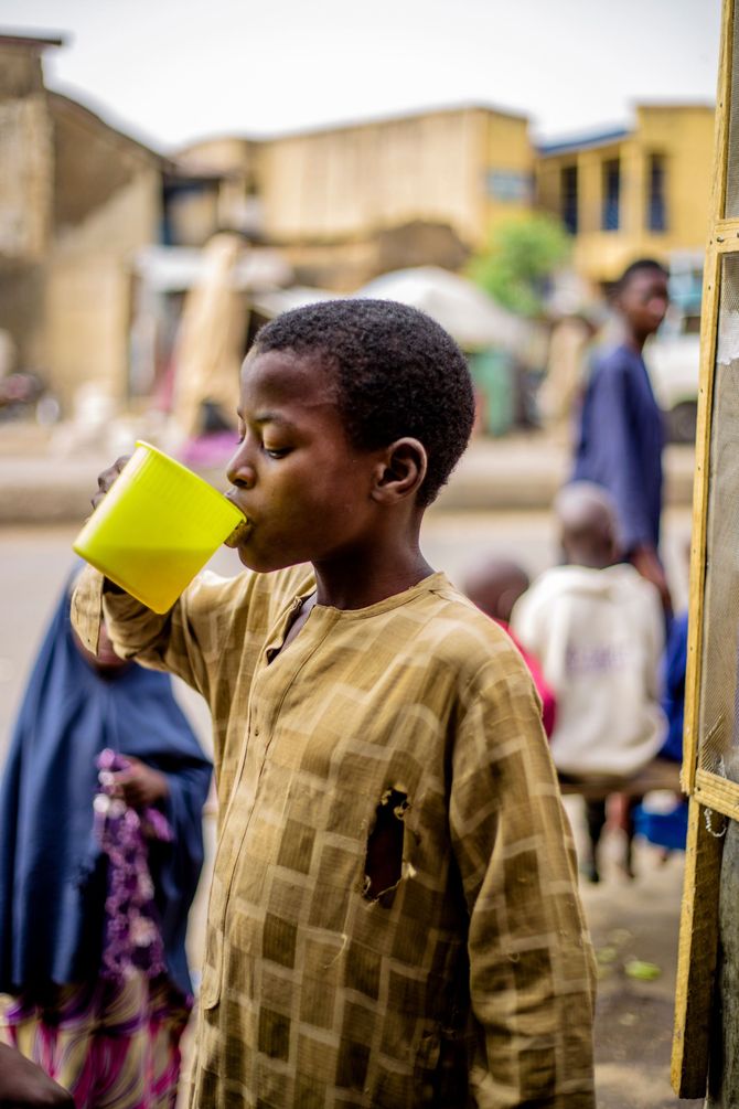 Child drinking from a bright green cup in a busy outdoor market street