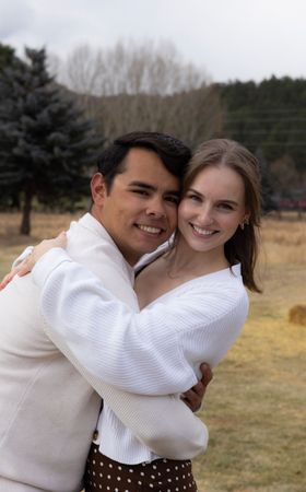 A man and a woman are hugging each other in a field.
