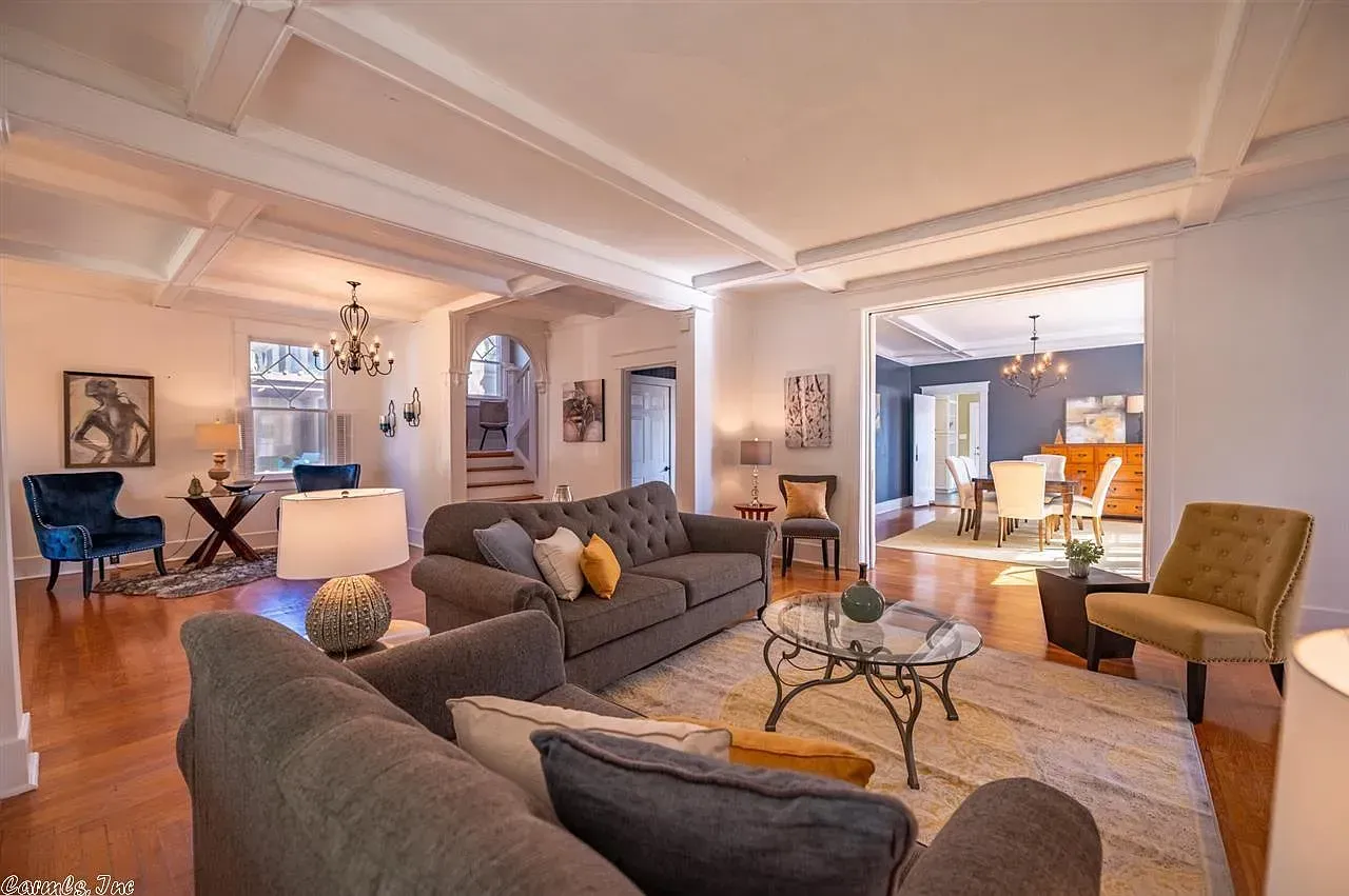 Spacious living room with gray sofas, hardwood floors, and access to other rooms.