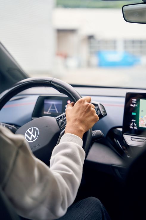 Eine Person fährt ein Auto und hat die Hände am Lenkrad.
