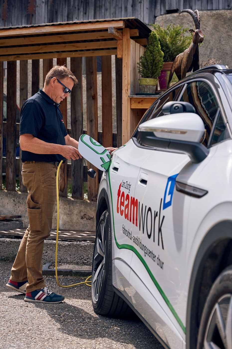 Lars  lädt ein Elektroauto auf, auf dessen Seite Teamwork steht