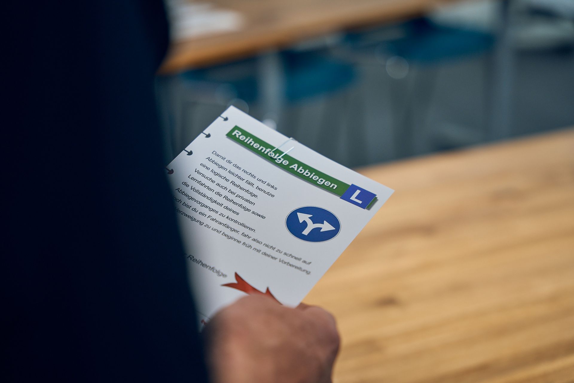 Eine Person hält ein Stück Papier mit Fahrschule Theorie Informationen