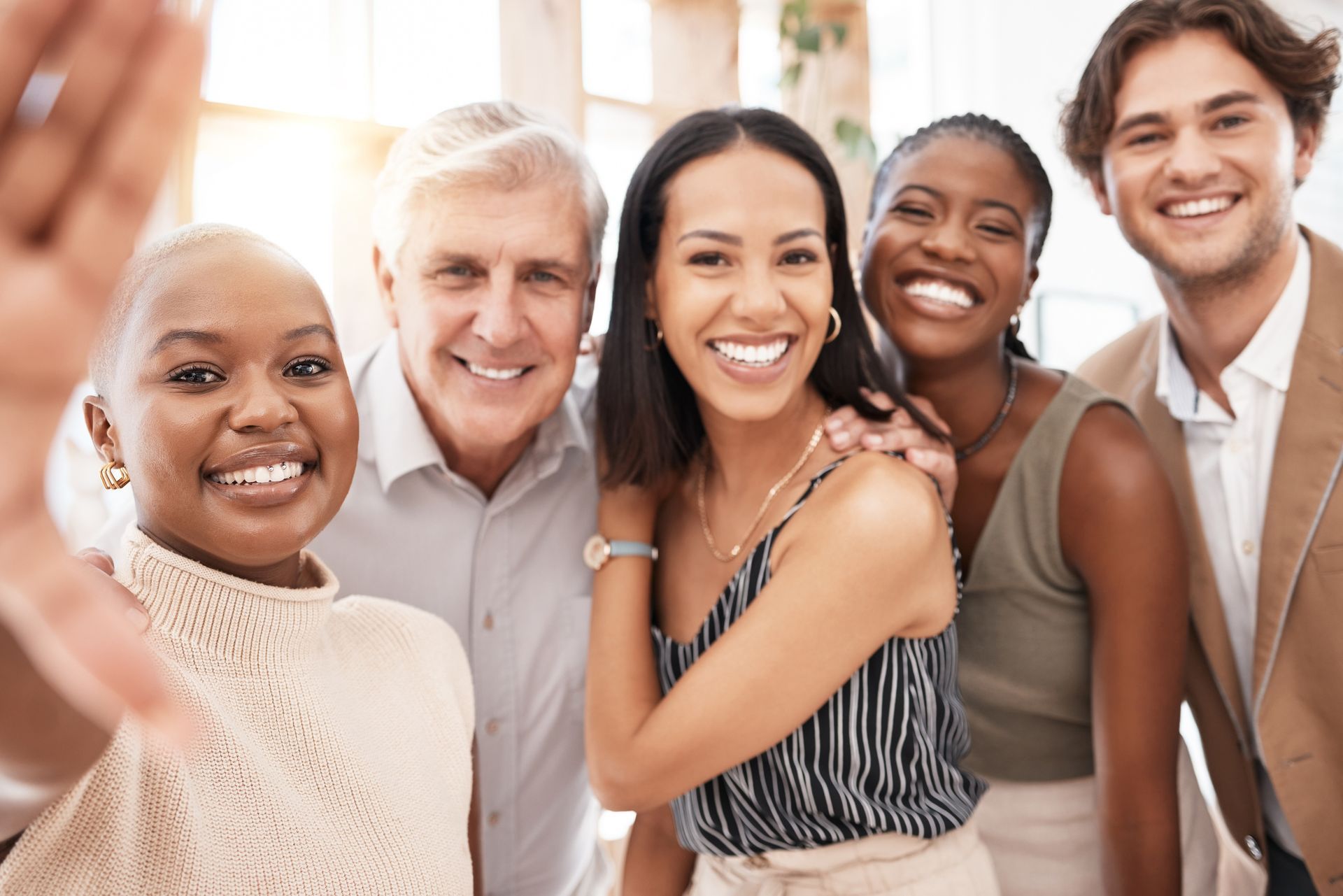 Five smiling people pose closely together in a bright indoor setting.