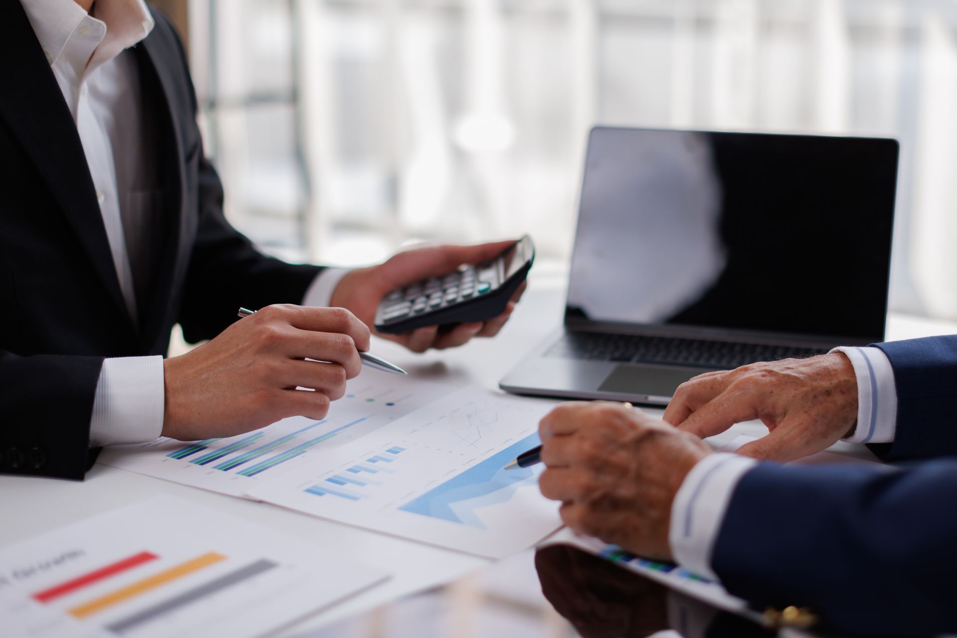Business meeting with two people reviewing charts and a laptop at a table