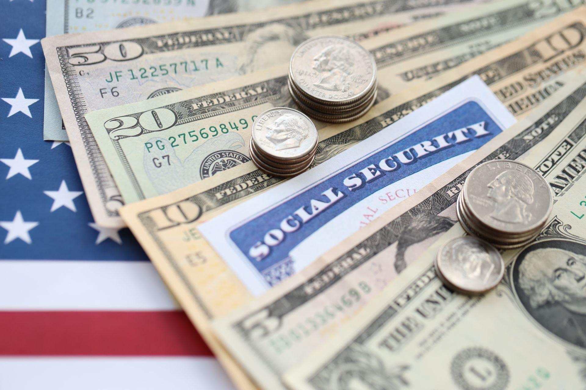 U.S. Social Security card with stacked coins and dollar bills on an American flag background