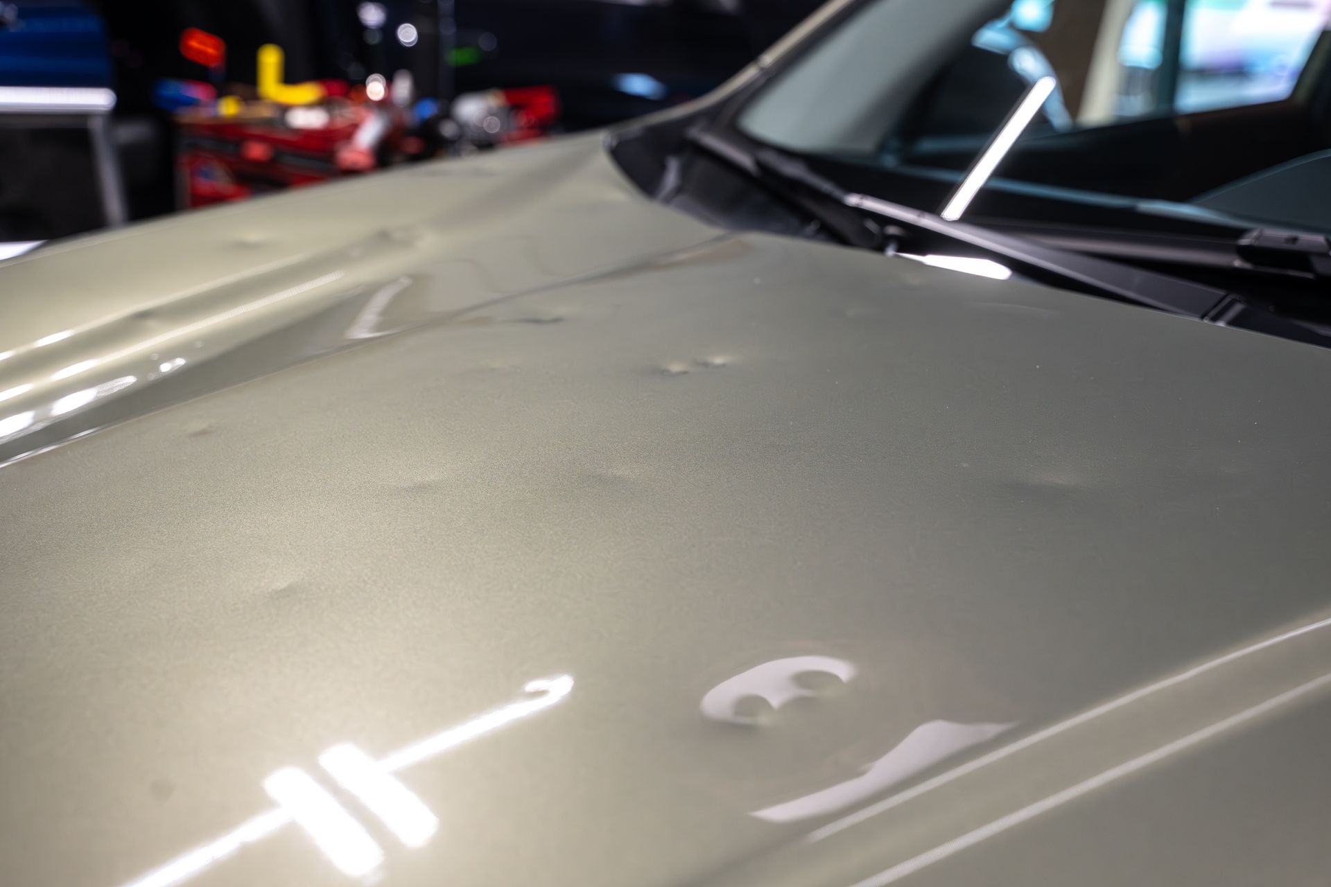 Car with dents preparing for the process of repairing hail damage in an auto body shop.