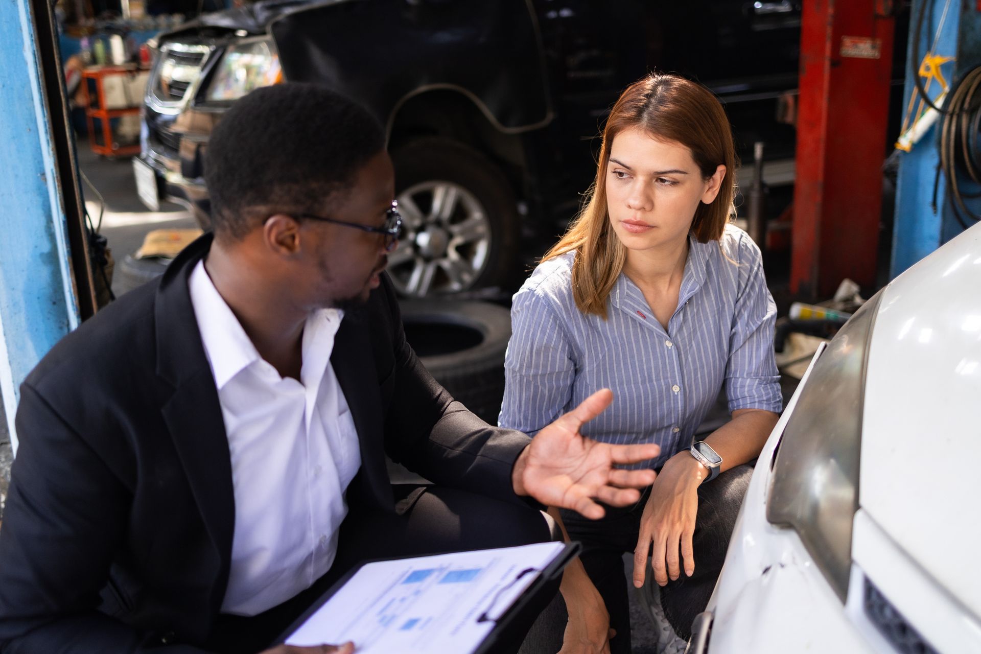 Two people discussing car maintenance in an auto repair shop.