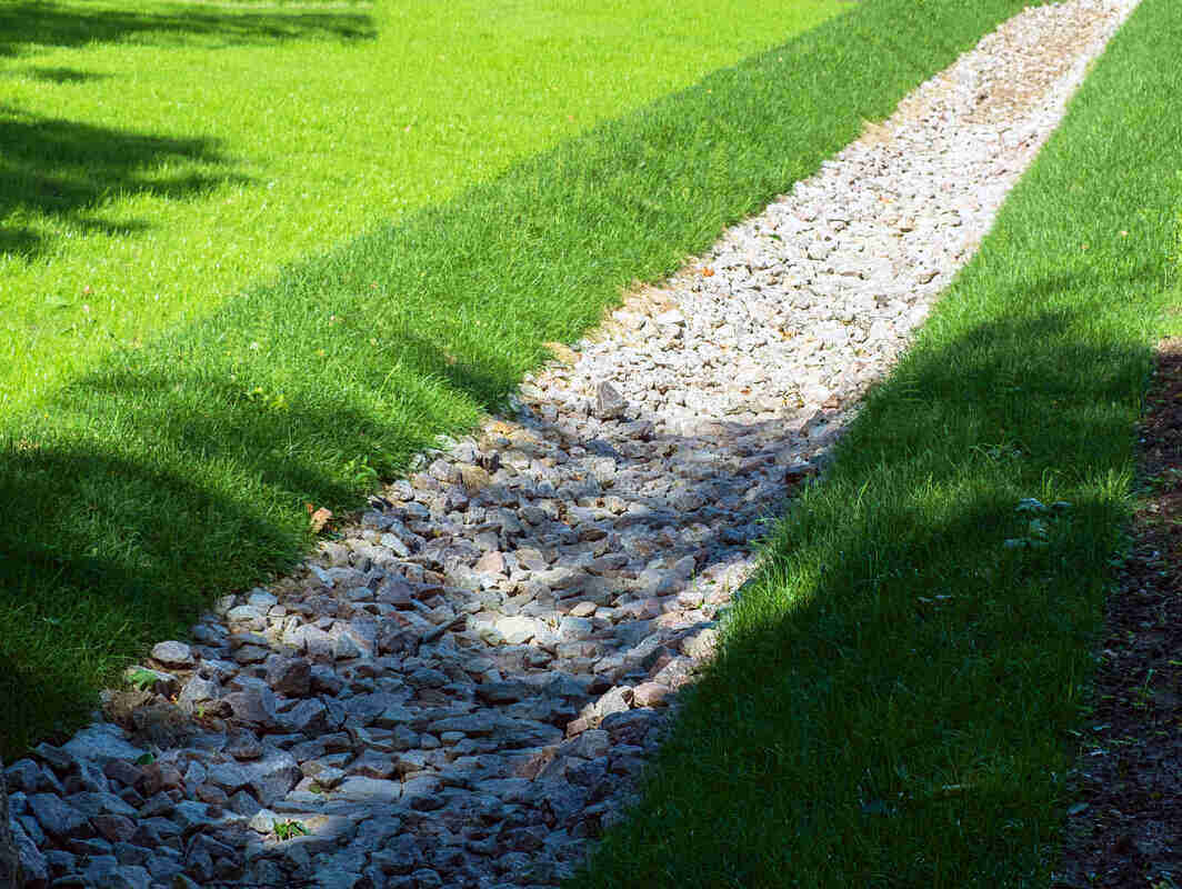 Gravel path cutting through bright green grass in sunlight