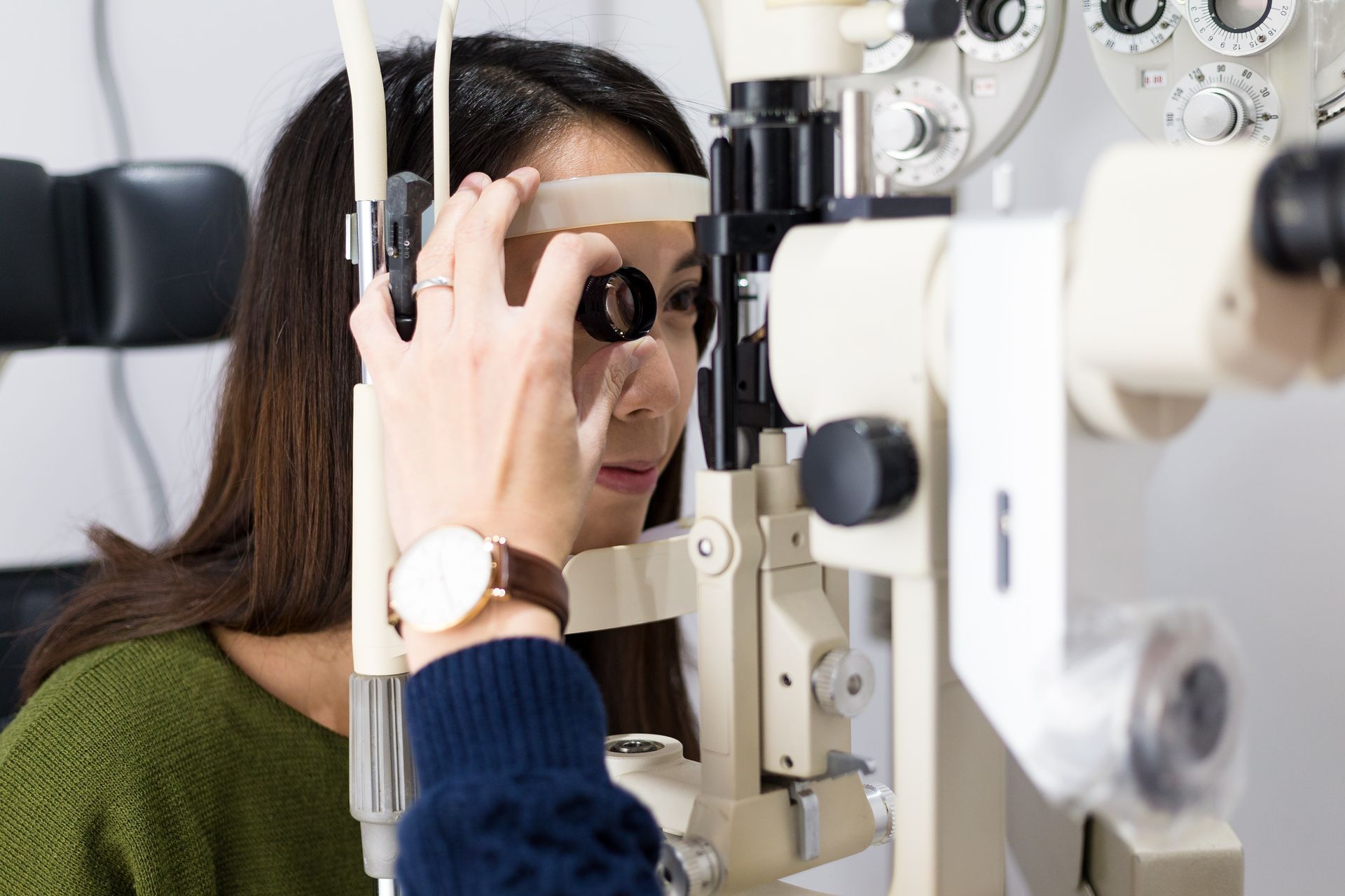 Woman checking vision with tonometer at eye clinic