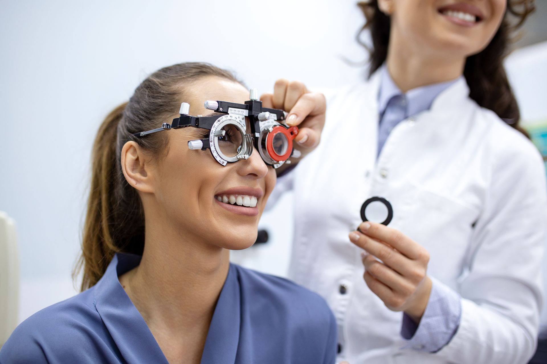Optometrist holding a trial lens in front of a patient’s eye during a vision test.