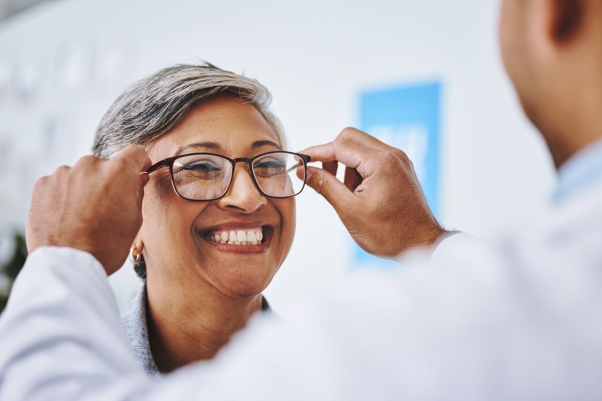 Smiiling woman getting glasses fitted by an expert providing comprehensive optometrist services. Smiiling woman getting glasses fitted by an expert providing comprehensive optometrist services.