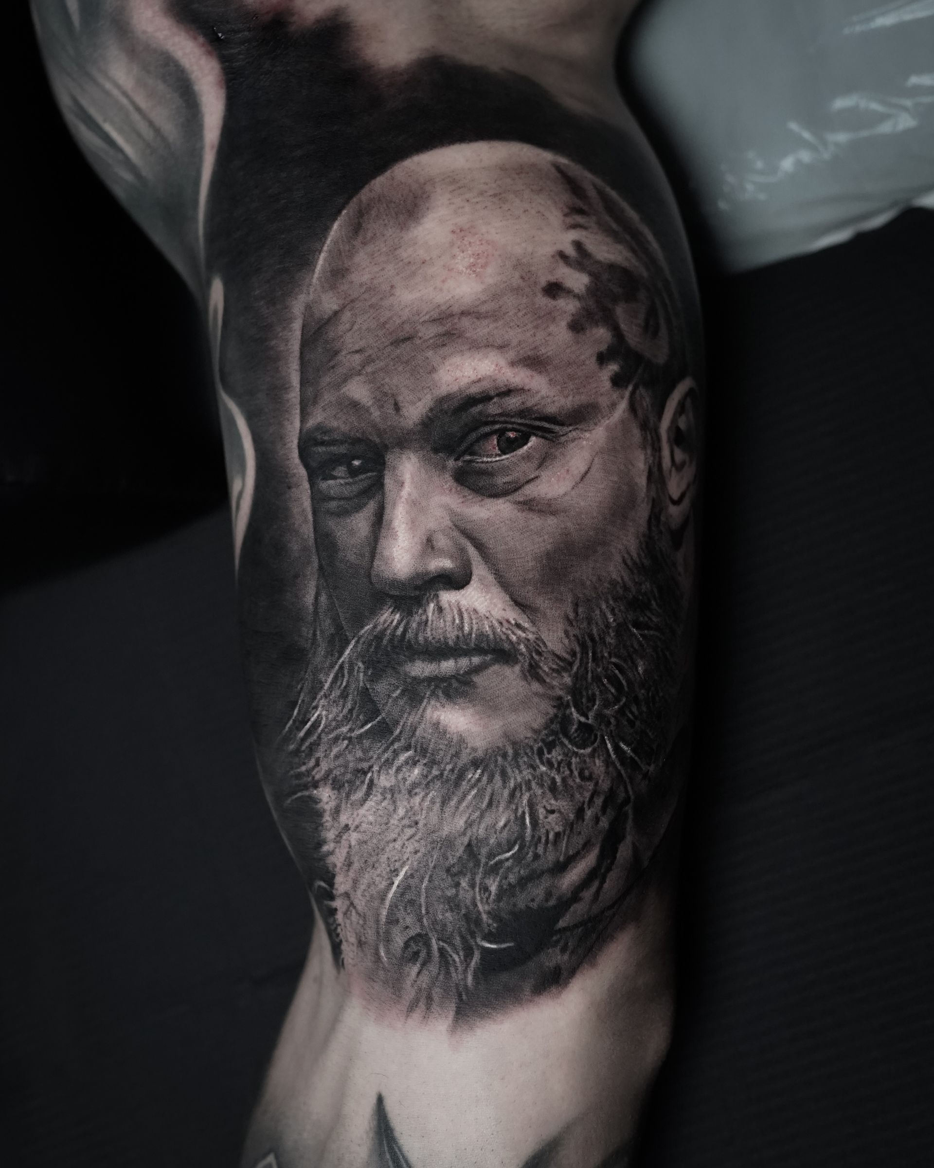 A black and white tattoo of a man with a beard on his arm.
