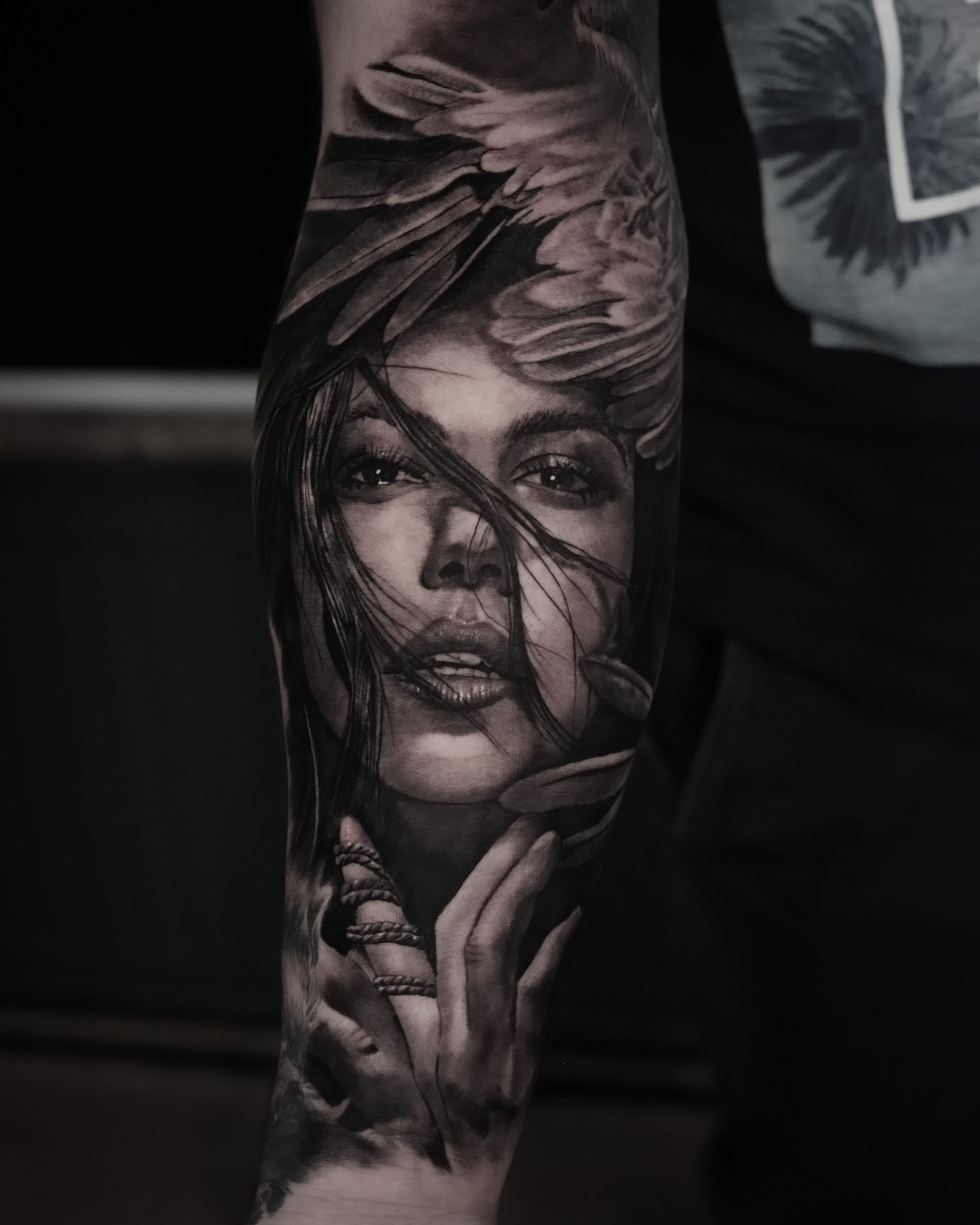 A black and white tattoo of a woman 's face on a man 's arm.