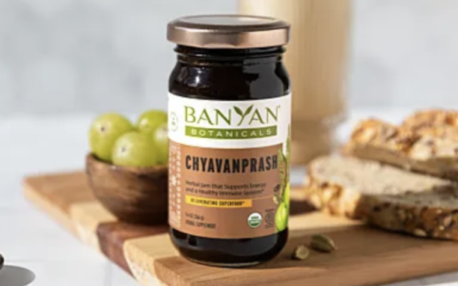 Banyan Botanicals Chyavanprash jar on a wooden board with green apples and bread slices