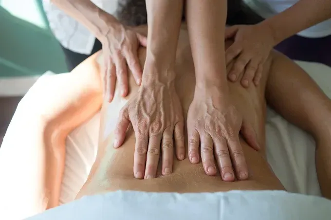 Massage therapist giving a back massage to a person lying face down on a table