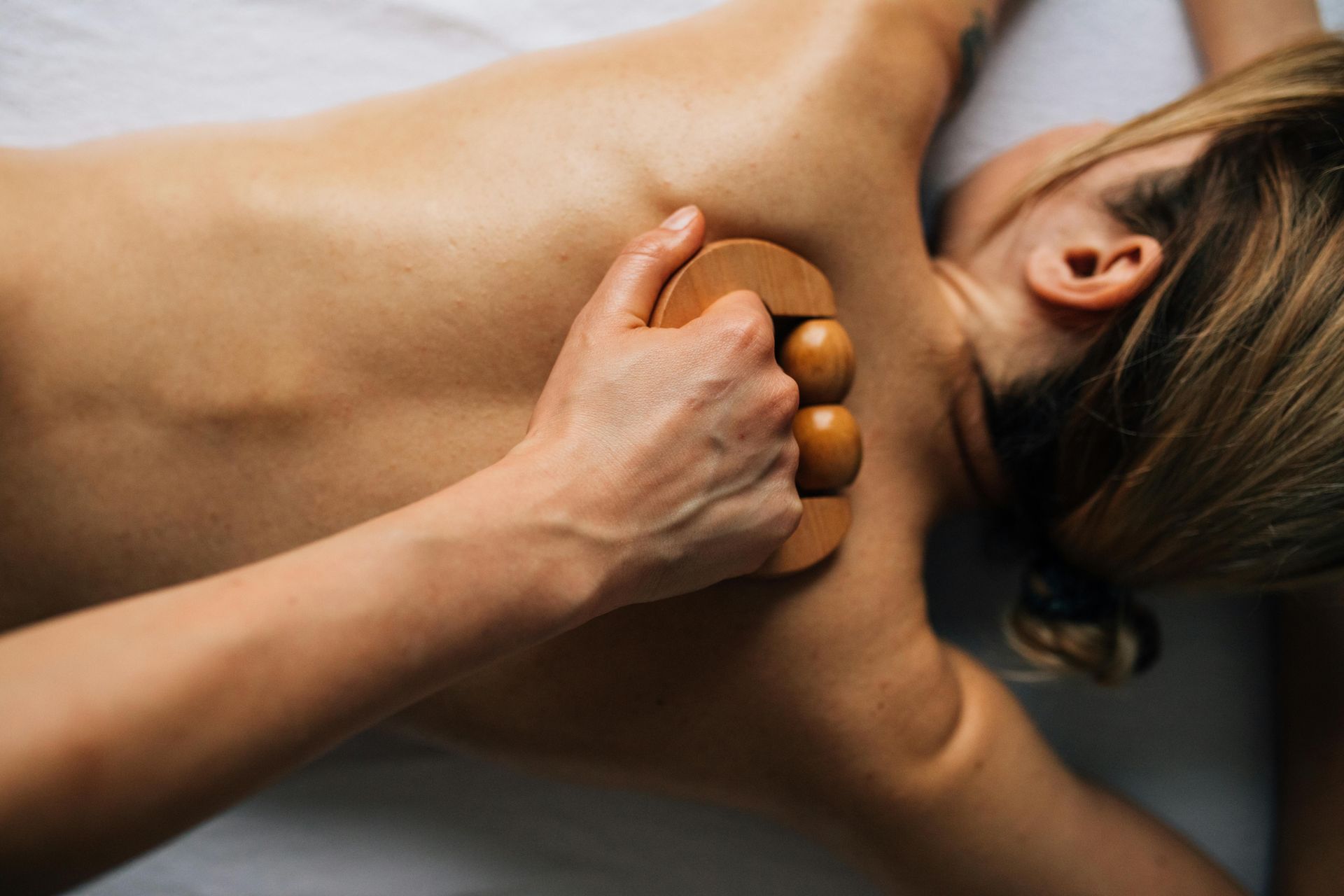 Massage therapist using hot stones on a person’s back and neck