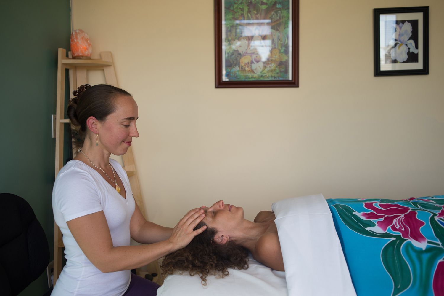 Hands massage a person’s back on a spa table.
