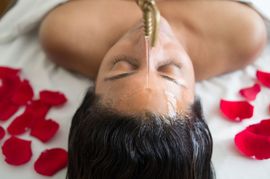 Oil being poured from a bottle onto a person’s back during a massage