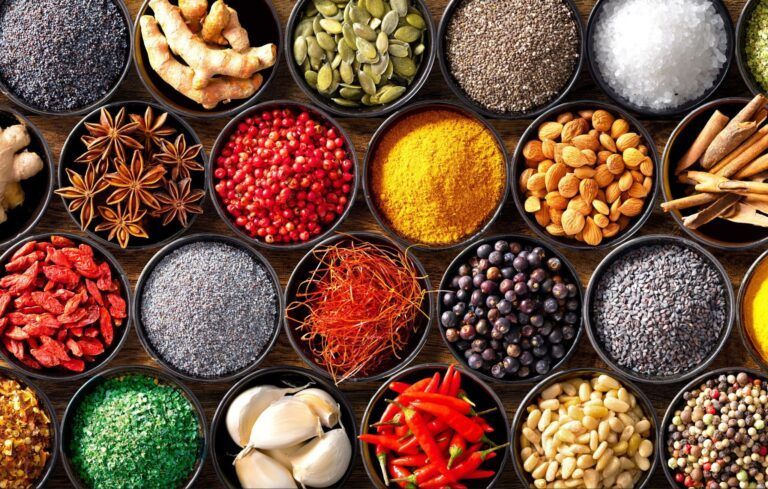 Assorted colorful spices and ingredients in bowls viewed from above